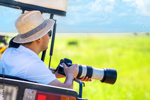 The man photographer takes a picture from touristic vehicle on tropical safari Canvas Print