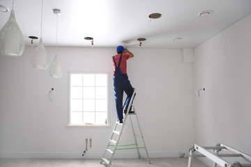 Canvas Print - Worker installing stretch ceiling in empty room