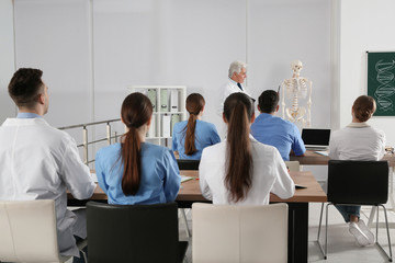 Poster - Medical students and professor studying human skeleton anatomy in classroom