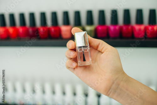 Cuadros en Lienzo girl holds nail polish on the background of nail polishes