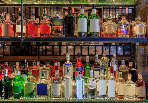 Selection of alcohol bottles on shelves on display at a bar, logos and labels removed. New York United States of America
