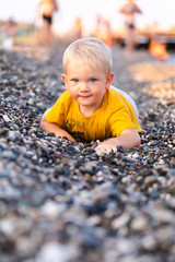 The boy lies on a pebble beach and looks at the sea