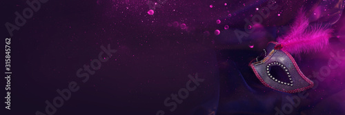 Fotomural Photo of elegant and delicate pink Venetian mask over purple silk background