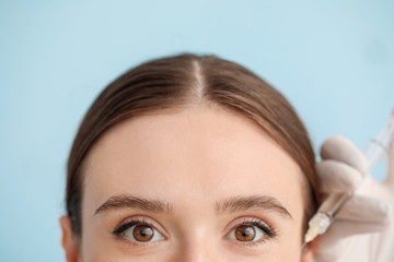 Wall Mural - Young woman receiving filler injection against color background, closeup