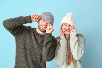 Wall Mural - Portrait of happy couple in winter clothes on color background