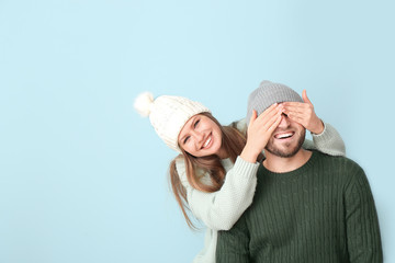 Wall Mural - Happy woman covering eyes of her boyfriend against color background