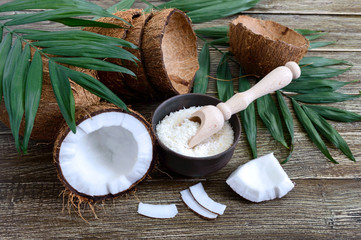 Wall Mural - Coconut. Whole coconut, shell, coconut flakes and green leaves on a wooden background. Big nut. Tropical fruit coconut in the shell. SPA.