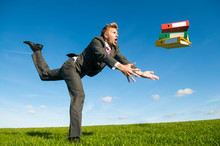 Clumsy Businessman Tripping Dramatically With His File Folders Flying Outdoors In A Green Grass Meadow