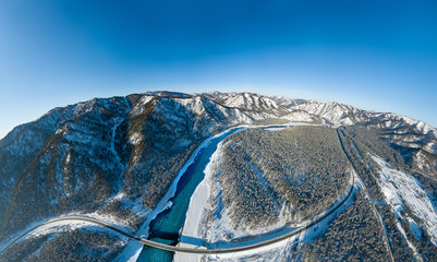 Panoramic aerial view nature and picturesque landscape near a Altay mountain with a green river Katun and bridge on a winter sunny day with blue sky