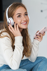 Sticker - Photo of young smiling woman using headphones and cellphone