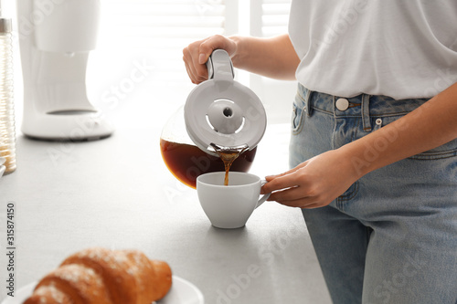Fotomural Woman pouring coffee into cup at home, closeup. Morning routine