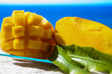 Fresh ripe sweet yellow mango fruit served on glass plate with blue seaview background