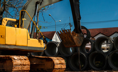 Using an excavator to transfer large pipes to a vehicle.