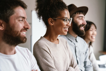 Image of multiethnic young business workers standing together at office