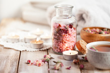 Concept Of Spa Treatment With Roses. Crystals Of Sea Pink Salt In Bottle, Candles As Decor. Atmosphere Of Relax And Pleasure. Anti-stress And Detox Procedure. Luxury Lifestyle. Wooden Background