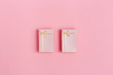 Two small pink gift boxes on pink paper background. Concept or greeting card minimal style. Romance top view background.