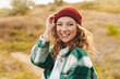 © Drobot Dean - Image of young woman wearing hat and plaid shirt walking outdoors