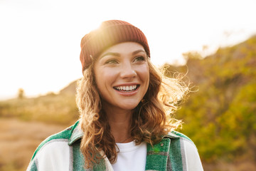 image of young woman wearing hat and plaid shirt walking outdoors