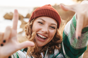 Canvas Print - Image of joyful young woman showing photo frame while walking outdoors