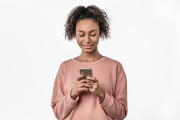 Wall Mural - Happy young afro american woman using mobile phone while standing isolated over white background