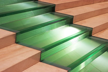 Wide Staircase With Green Glass Steps Between Brown Stone Stepe