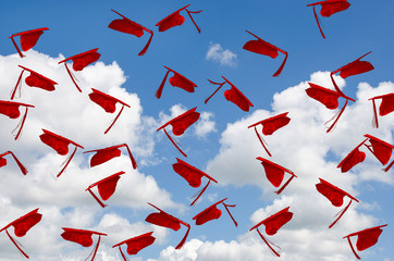 Wall Mural - airborne red graduation hats with tassels in summer blue sky