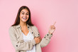 Young caucasian woman posing in a pink background smiling cheerfully pointing with forefinger away.