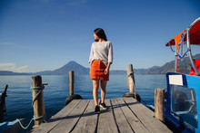 Hispanic Traveling Girl On The Pier Of Lake Atitlan In Guatemala - Hispanic Woman Observing The Landscape On The Blue Lake Of Latin America - Young Adventurer