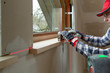 © artursfoto - home improvement handyman installing window sill in new build attic by using leveler and laser leveler