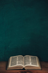 Aufkleber - Open bible on a red old wooden table. Beautiful green wall background.