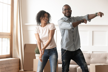 Wall Mural - Happy millennial african american couple dancing in living room.