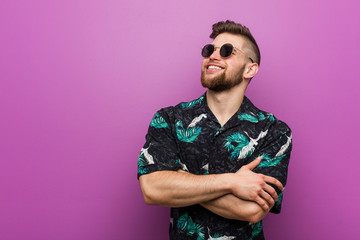 Young man wearing a vacation look smiling confident with crossed arms.