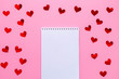 White blank notebook with red hearts confetti on pink background