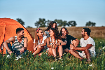 group of friends having fun outside tents on camping holiday