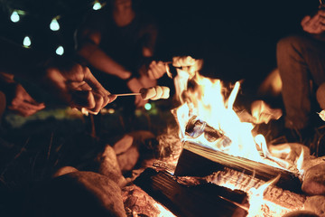 romantic night. young people roasting marshmallows over a campfire while enjoying their road travel