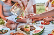 © HBS - Male hands pouring lemonade from the decanter into a glass tumbler, glass pitcher with slices of grapefruit, lime, water, mint leaves