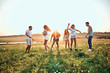 © HBS - Six friends dancing, cheering on a green meadow near lake, being happy about vacation.