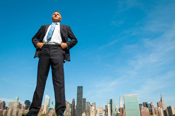 giant businessman standing tall in dark suit above the city skyline