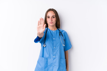 Wall Mural - Young nurse woman isolated standing with outstretched hand showing stop sign, preventing you.