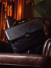 A Black Leather Business Briefcase Sits On A Leather Chair