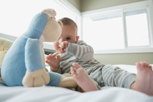 Baby With Stuffed Animal On Bed