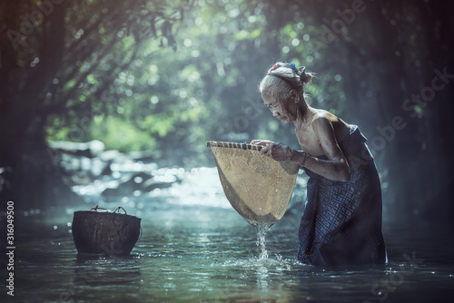 Cuadros en Lienzo Old Asian woman working in creek, Thailand countryside