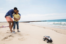 Father And Son Playing Remote Control Truck Beach