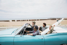 Young Couples Riding In Convertible With Surfboard Beach