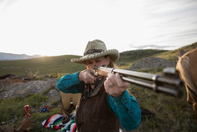 Female Rancher Aiming Rifle In Remote Field