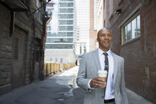 Businessman With Coffee Walking In Urban Alley