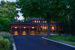 Red brick house with circular driveway and triple garage at dusk