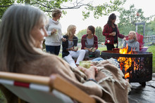 Women Relaxing Around Fire In Backyard