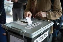 Woman Placing Ballot In Ballot Box Polling Place