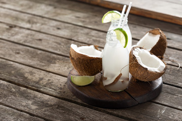 Wall Mural - Coconut water in bottles on wooden table. Healthy veggie drink